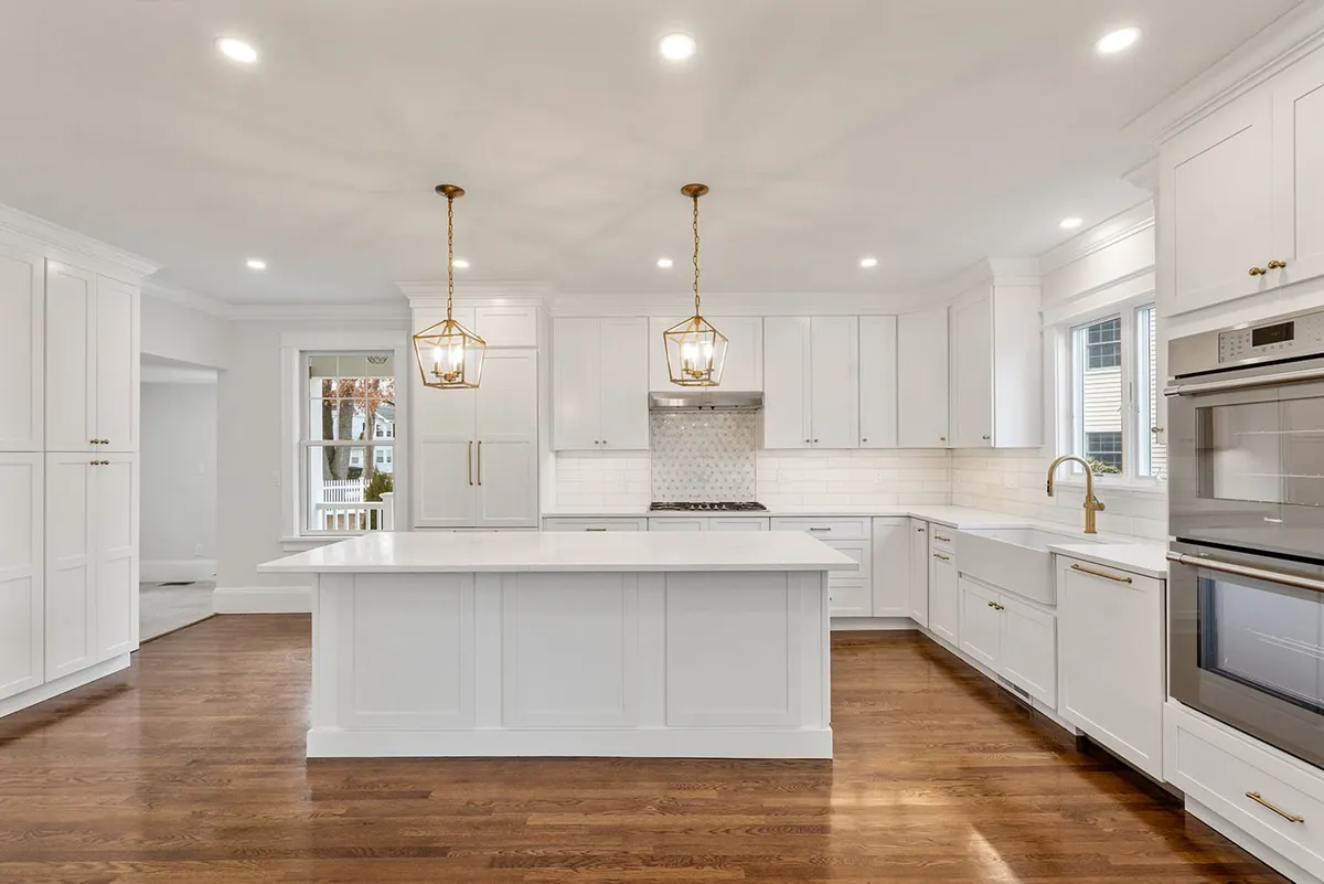Bright white kitchen with gold lantern pendants and a marble island, a Bay State project in Newton