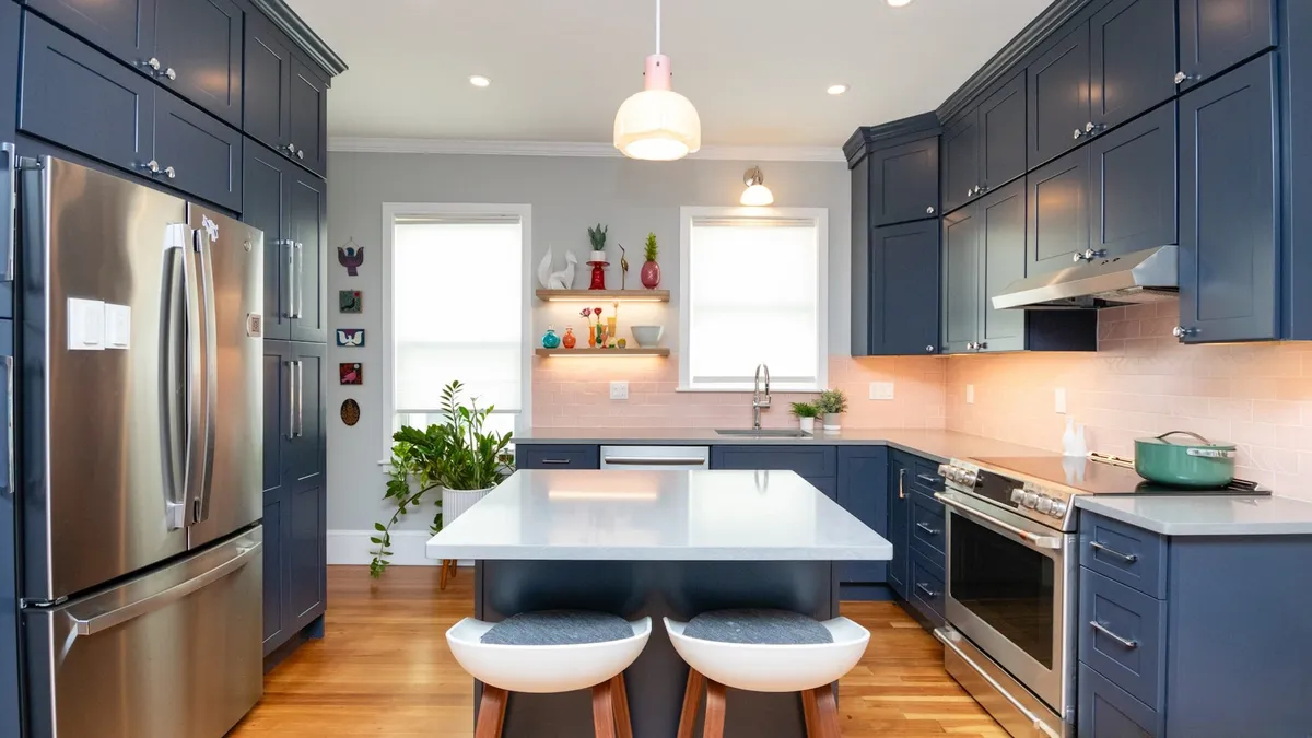 Jamaica Plain kitchen with navy shaker cabinets, a white quartz island, pink subway tile, and a stainless fridge